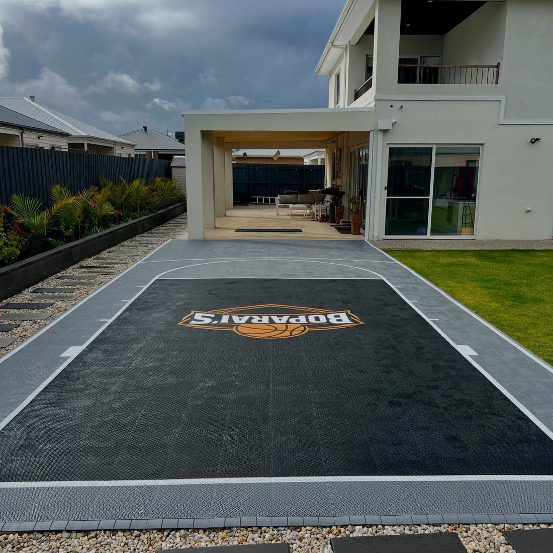 Custom shaped backyard sports court fitted alongside a modern home