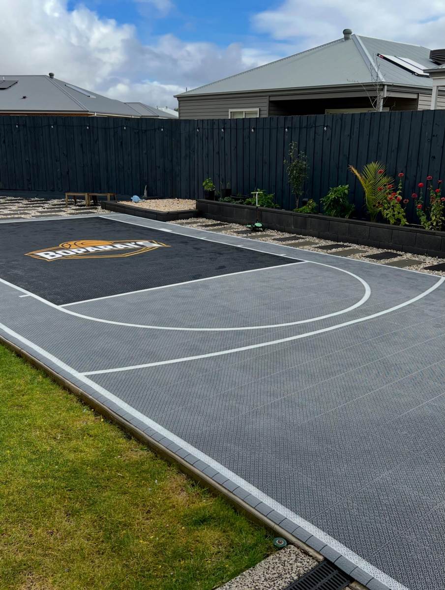 Large grey backyard basketball court with white line markings